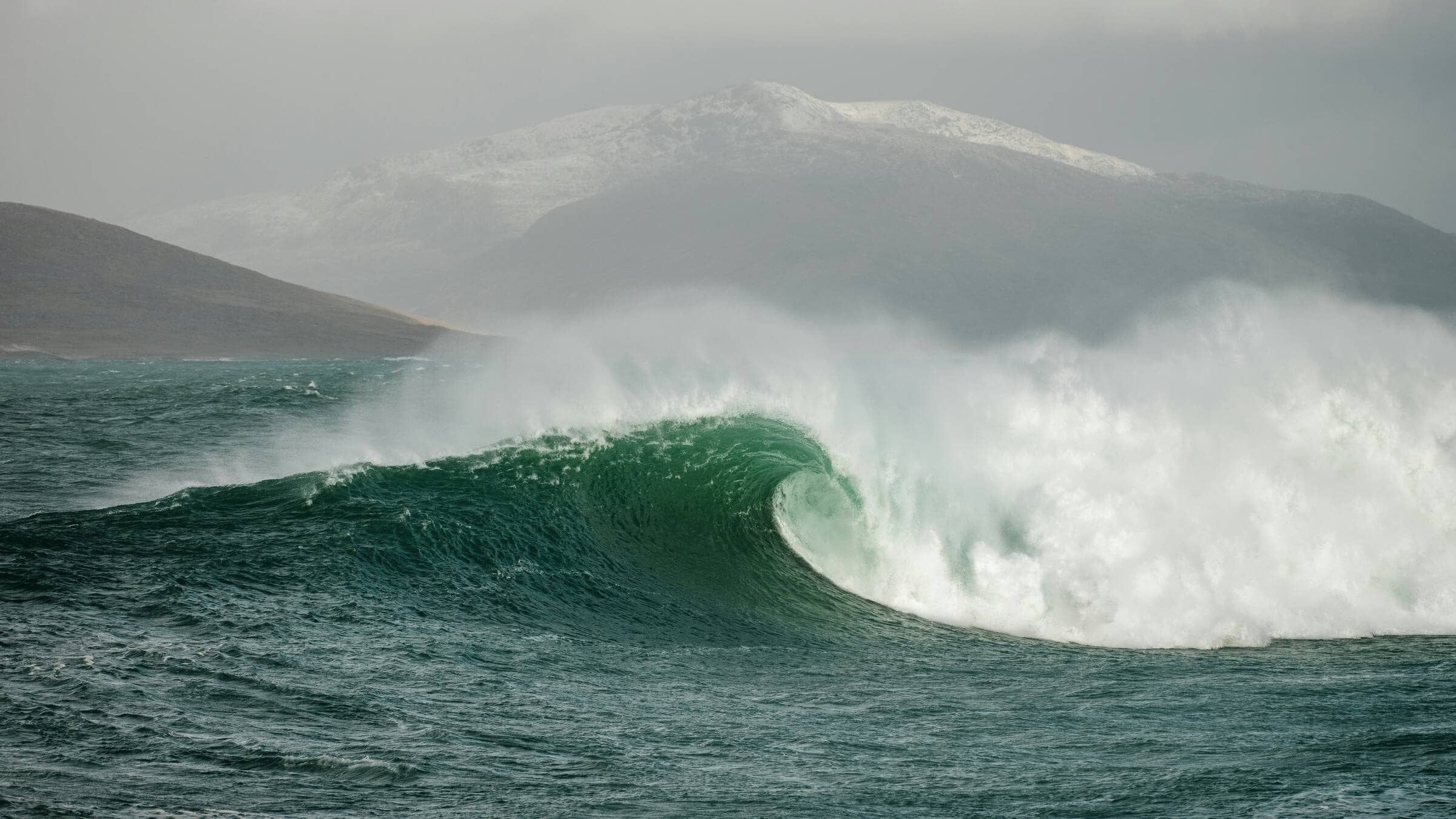 photo of a wave with mountains in background